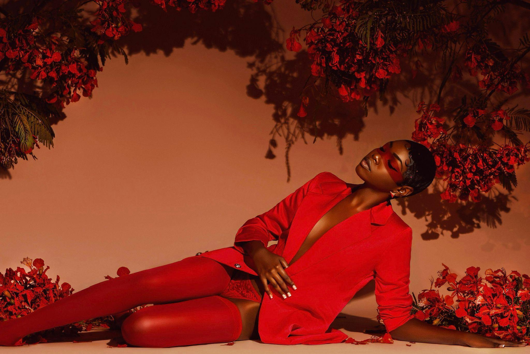 Model in red couture surrounded by red foliage - horizontal composition
