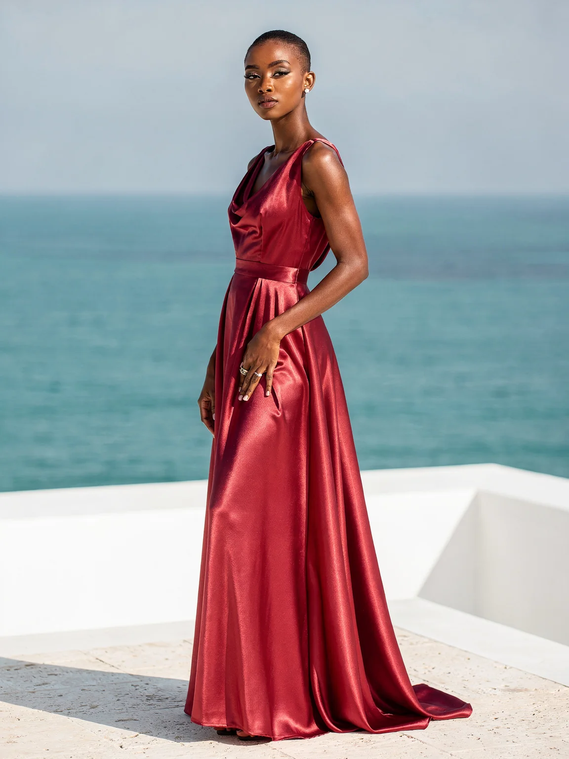 A woman in a rose-red satin gown on a white terrace above the sea