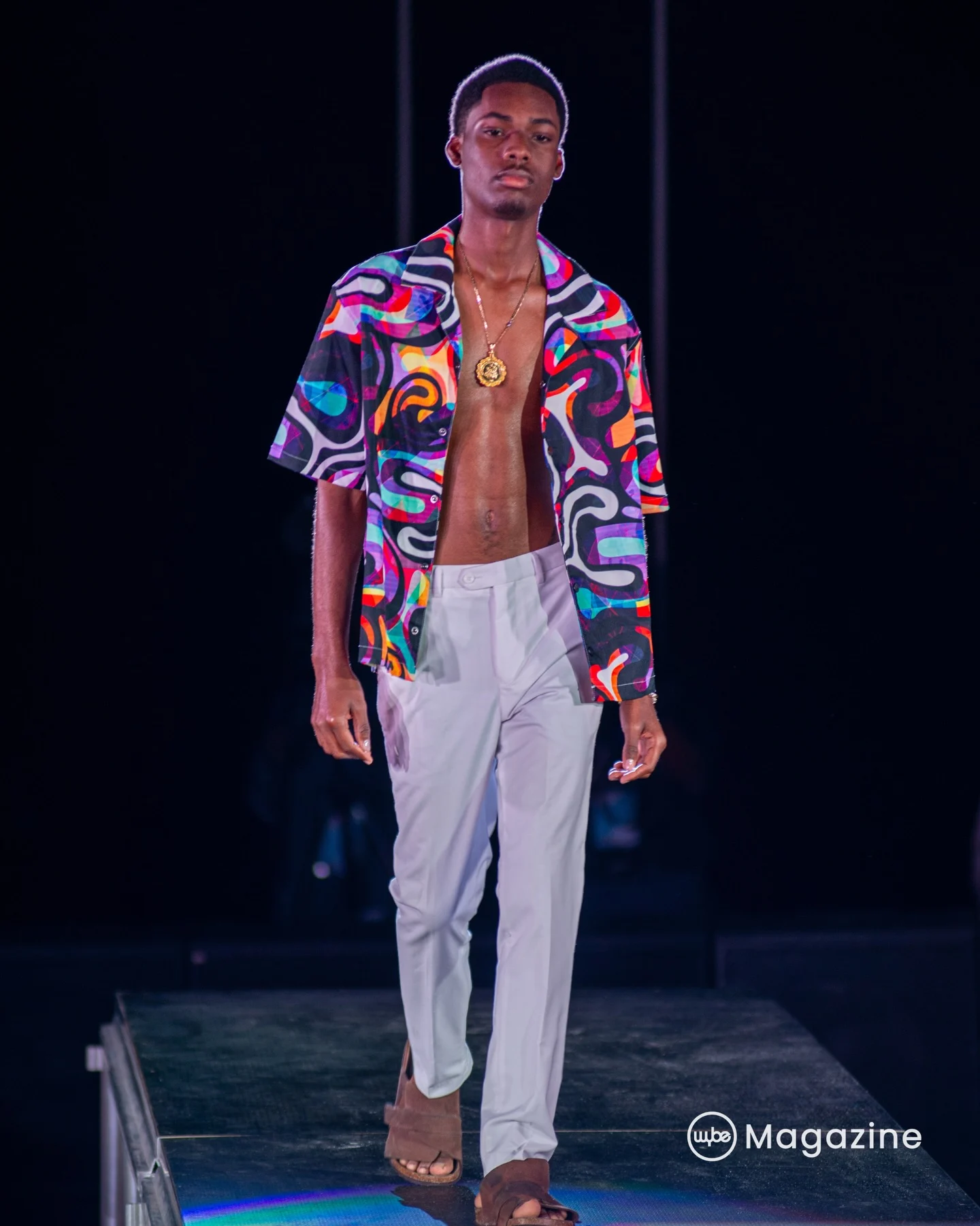 Abstract-print camp shirt: A vivid, swirling print worn open over crisp white trousers.